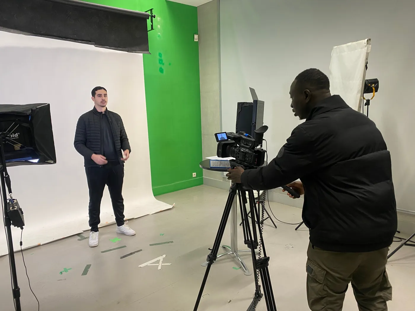 Maname Wade filme une interview en studio, caméra sur trépied et fond vert