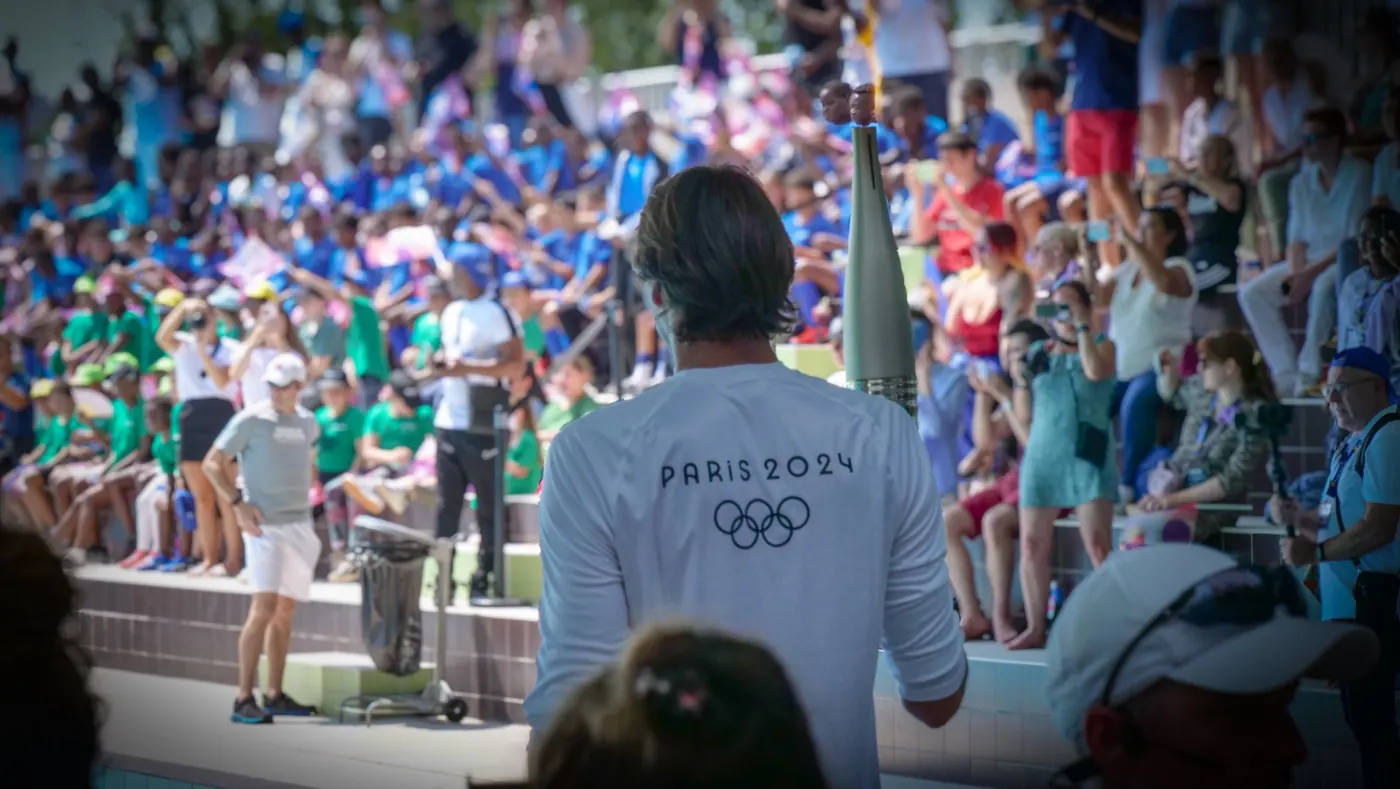 Porteur de la flamme olympique Paris 2024 face à une foule en tribune