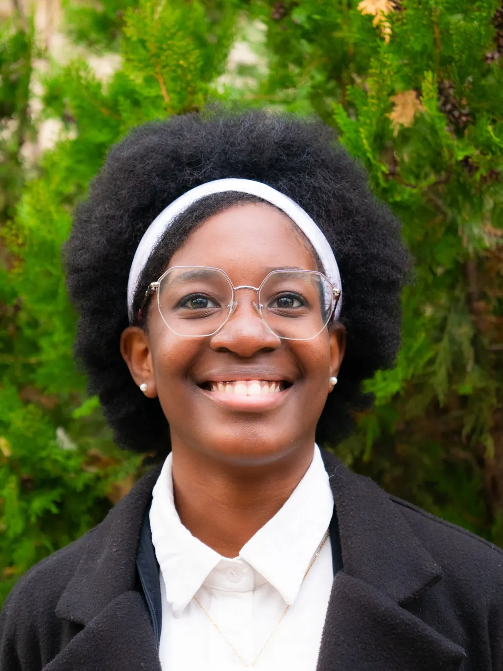 Portrait souriant d’une jeune femme devant un feuillage vert